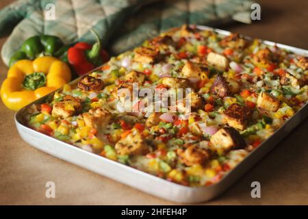 Pizza fatta in casa con paneer, mozzarella, peperoni rossi gialli verdi e cipolle. Cotto in un vassoio rettangolare Foto Stock