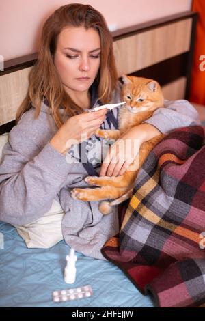 Donna con termometro e medicinali a letto. Malattie respiratorie. Foto Stock