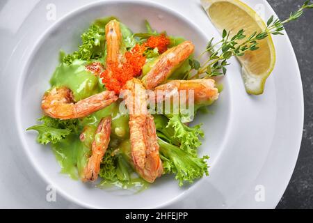 Gamberi fritti con caviale, erbe e salsa, su un piatto bianco Foto Stock