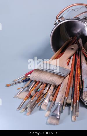 Strumenti di creatività - un mazzo di grungi pennelli del pittore in un secchio di metallo su sfondo blu Foto Stock