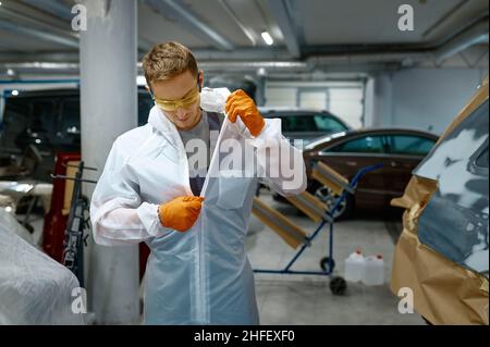 Il tecnico scollega il vestito protettivo dopo il lavoro di finitura Foto Stock