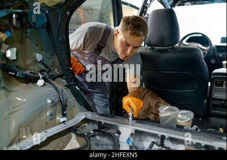 Operatore automobilistico impegnato nel lavoro della carrozzeria dell'auto Foto Stock