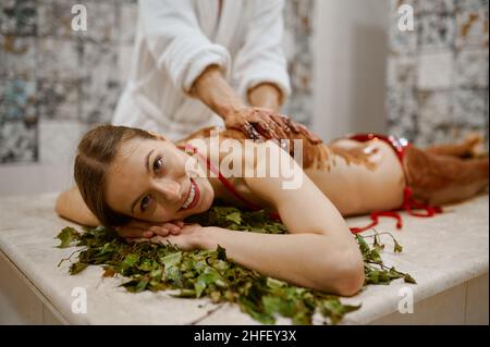 Giovane donna che ottiene il massaggio del miele nella sauna Foto Stock