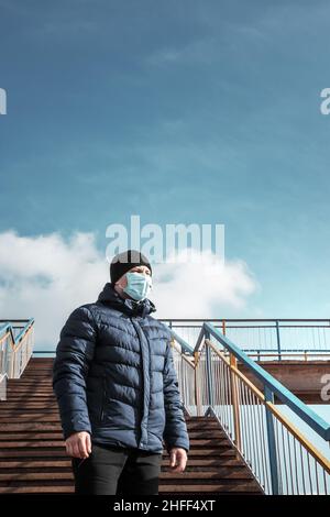 ritratto di uomo di brunette in un bendaggio chirurgico su sfondo di un edificio, coronavirus, malattia, infezione, quarantena, maschera medica Foto Stock