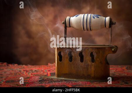 Antico ferro di carbone vittoriano in piedi su tessuto vintage Foto Stock