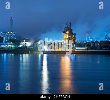 Vista notturna di uno stabilimento dell'industria chimica con banchina in primo piano Foto Stock