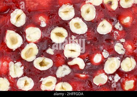 Delizia turca con nocciole e succo di melograno da vicino. Dadi nella vista superiore del succo rosso. Dolci orientali con fondo nocciola. Foto Stock