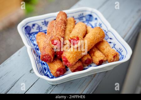 Churros ripieno di ciliegia fresca in ciotola quadrata sul portico Foto Stock