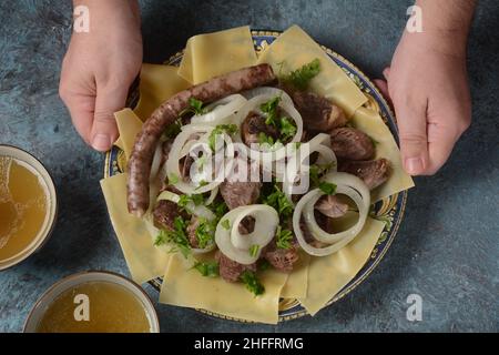 Beshbarmak - piatto nazionale kazako, preparato con carne e pasta. Piatto di Beshbarmak primo piano su un piatto sul tavolo. Grandi pezzi di carne stufata e oni Foto Stock