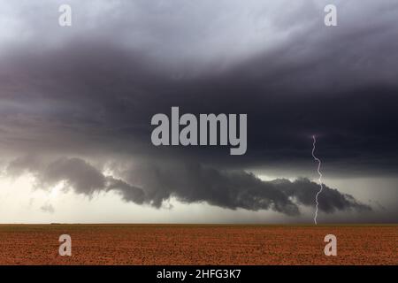 Nuvole ominose e fulmini colpiscono sotto una drammatica tempesta di tuore su un campo agricolo vicino a Lamesa, Texas Foto Stock