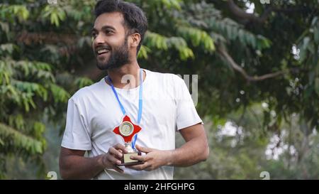 indian Smart Collage, ragazzo scuola con medaglia d'oro e coppa trofei Foto Stock