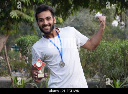 indian Smart Collage, ragazzo scuola con medaglia d'oro e coppa trofei Foto Stock