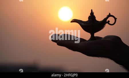 lampada magica in mano con luce solare jinee concetto magico Foto Stock