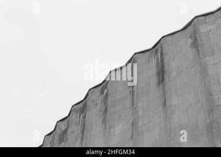 Cemento vecchio edificio architettura struttura cemento facciata appartamento pietra con elementi di illuminazione bulbi sul tetto su uno sfondo di gra Foto Stock