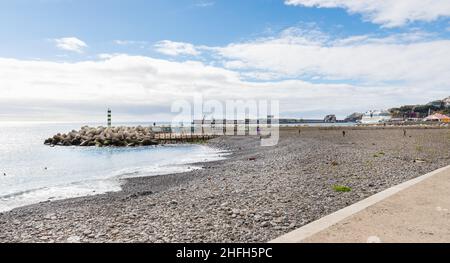 Funchal, Madeira, Portogallo - 27 dicembre 2021: Le persone che passeggiando, camminando, facendo il bagno o riposandosi sulla spiaggia di Almirante Reis in una giornata invernale Foto Stock