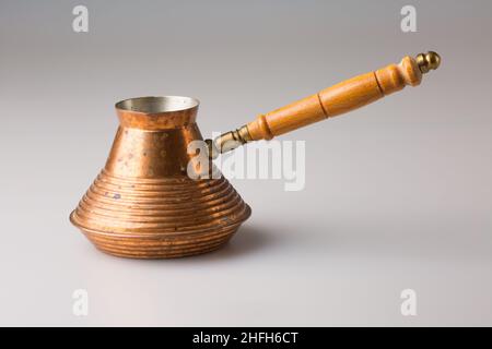 Cezve in rame per la preparazione del caffè. Isolato su sfondo grigio. Foto Stock