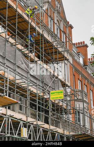 Londra, Inghilterra - Giugno 2020: Operai edili che smantellano i ponteggi all'esterno di un edificio in fase di ristrutturazione Foto Stock