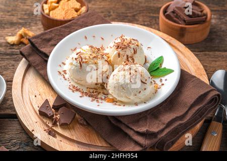 Gelato cremoso con gocce di cioccolato e biscotti su sfondo di legno. Vista laterale, primo piano. Dessert estivo. Vista laterale, primo piano. Dessert estivo. Foto Stock