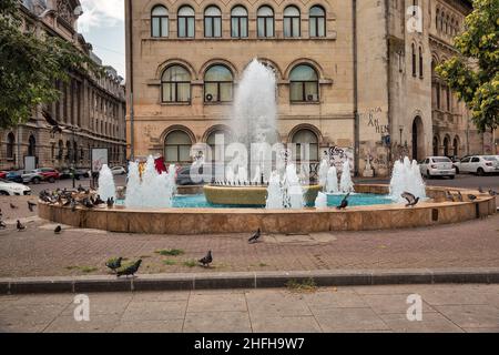 Bucarest, Romania - 12 agosto 2021: Fontana decorativa piena di piccioni vicino alla Piazza dell'Università. Bucarest è la capitale e culturale, ind Foto Stock