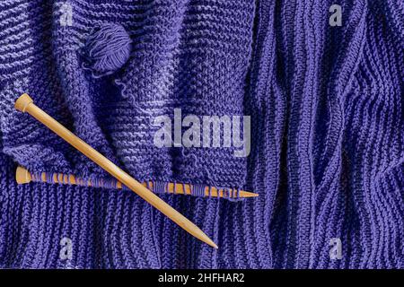 Palla di filo di lana viola, aghi di legno per maglieria sulla vista sciarpa lilla dall'alto. Hobby creare sfondo con spazio per il testo. Nozione di maglia, Foto Stock