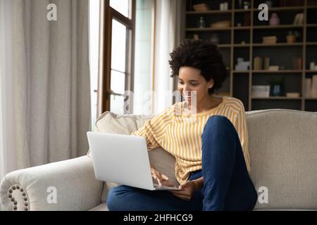 Felice bella millenaria donna afroamericana usando il computer. Foto Stock