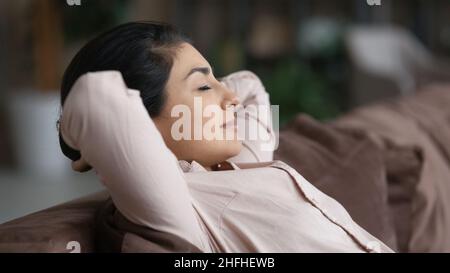 Tranquilla felice giovane indiana donna riposante su un comodo divano. Foto Stock