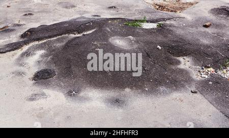 Una strada danneggiata da pioggia e neve, che necessita di manutenzione. Pavimentazione asfaltata rotta con conseguente buche, pericolosa per i veicoli. Foto Stock