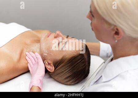 La donna estetista pulisce e idrata la pelle del paziente in un salone termale. Foto Stock