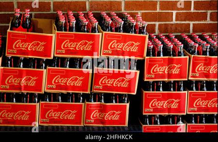 Casi di Coca-Cola in bottiglie di vetro su Brick Wall Foto Stock