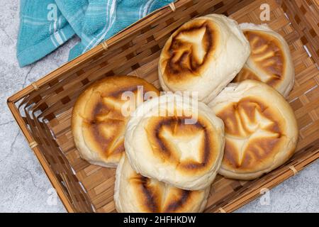 Muffin inglesi monano un tovagliolo in un cestino di vimini. Su sfondo concreto Foto Stock
