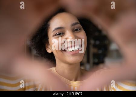 Primo piano gioiosa giovane afroamericana che fa segno di cuore. Foto Stock