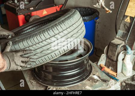 Meccanico che ripara una ruota che ha rimosso da un'auto Foto Stock