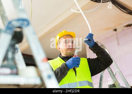 Elettricista che lavora con i fili in appartamento Foto Stock