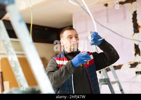 Elettricista che lavora con i fili in appartamento Foto Stock