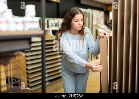 Cliente femmina che tiene campioni di pannelli di legno nel negozio di ferramenta Foto Stock