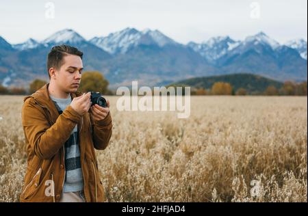 L'uomo è un fotografo nel campo scatta una foto su una vecchia telecamera da film retrò. Foto Stock