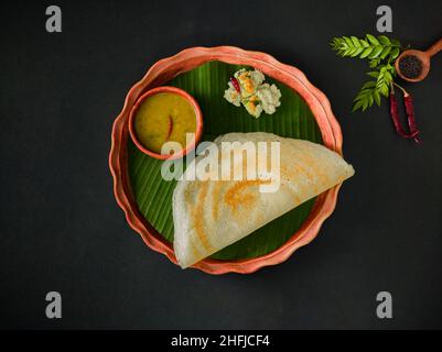 tradizionale cibo sud indiano masala dosa, sambar e chutney di cocco servito su piatto di argilla e foglia di banana. studio shot. copia sfondo spazio. Foto Stock