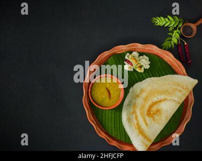 tradizionale cibo sud indiano masala dosa, sambar e chutney di cocco servito su piatto di argilla e foglia di banana. studio shot. copia sfondo spazio. Foto Stock