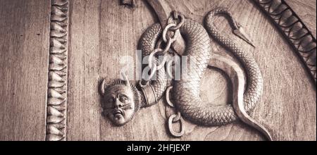 Serpente diavolo simbolo. Fantasia creatura magica su una vecchia porta, 12th secolo Abbazia, Italia. Foto Stock