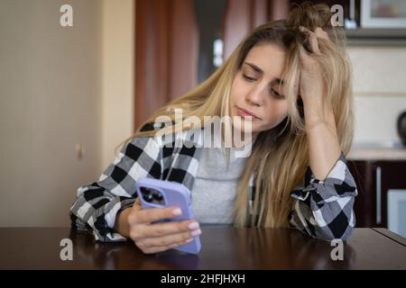 Solitario triste ragazza è in attesa di una telefonata, seduto al tavolo a casa. Depresso. Spazio copia. Foto Stock