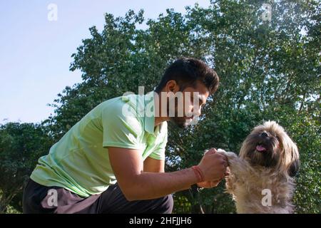 giovane che gioca con il cane al parco Foto Stock