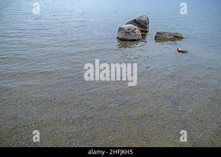 riva del lago poco profonda, con pietre grandi e piccole Foto Stock