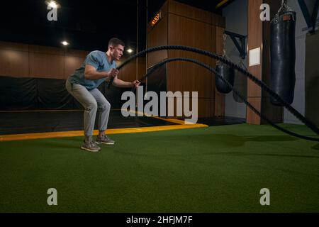 Uomo sportivo concentrato e serio che fa l'allenamento del corpo intero Foto Stock