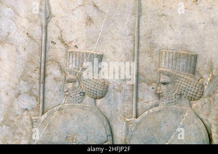 Antico muro con bassorilievo con guerrieri assiri con lance e scudi, Persepolis, Iran. Sito patrimonio dell'umanità dell'UNESCO Foto Stock