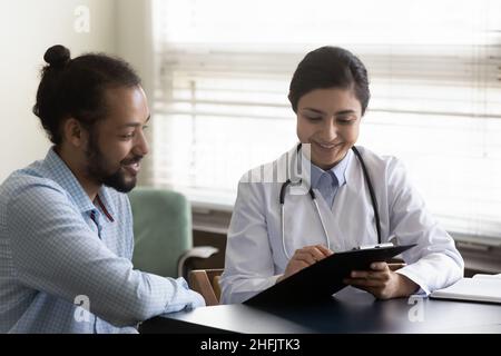 Felice giovane medico indiano che comunica con il paziente. Foto Stock