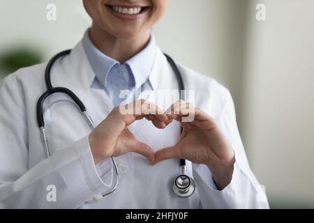 Primo piano giovane medico indiano felice facendo gesto di cuore. Foto Stock