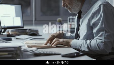 Uomo d'affari che controlla le notizie del mercato azionario su un giornale finanziario Foto Stock