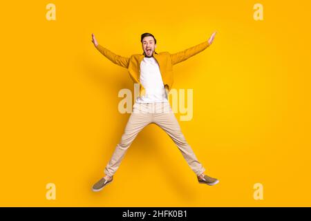 Foto a tutta lunghezza di gentleman grazioso dolce vestito casual vestito sorridendo saltando alto come stella isolato colore sfondo giallo Foto Stock