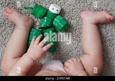 riutilizzo dei materiali. Un bambino gioca un giocattolo robot fatto di tappi di plastica per biberon. Foto Stock