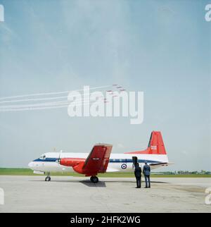 Aeroporto di Birmingham, Birmingham Maglev, Elmdon, Birmingham, Bickenhill, Solihull, 30/05/1984. Un velivolo Hawker Siddeley Andover sulla pista all'Aeroporto Internazionale di Birmingham, con le frecce rosse che volano in alto. La costruzione di un nuovo edificio terminale, le estensioni a piste, grembiuli e una nuova barriera antirumore all'aeroporto di Birmingham sono iniziate nel maggio 1981. Inoltre è stato costruito un blocco di servizi, moli rialzati, una stazione dei vigili del fuoco, una torre di controllo, e il sistema Maglev che collega l'aeroporto con la stazione ferroviaria di Birmingham. La cerimonia ufficiale di consegna si è svolta nel gennaio 1984 e il sito è stato ufficialmente aperto Foto Stock